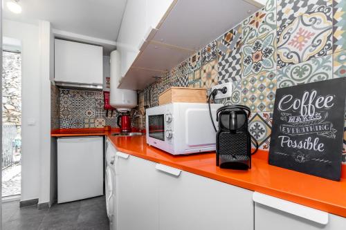 cocina con encimera y microondas en Apartamento com escada e pátio, em frente praia en Paço de Arcos