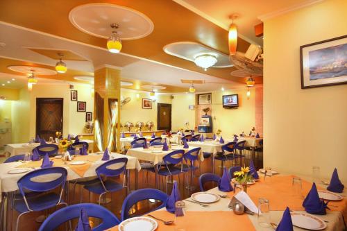 a banquet hall with tables and blue chairs at Sun Hotel-Haridwar in Haridwār
