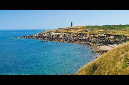 a body of water with a lighthouse on a hill at Jolie maison à la campagne « Chez Germaine » in Digosville