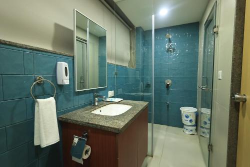 a blue bathroom with a sink and a shower at SN Blu Hotel in Ahmedabad