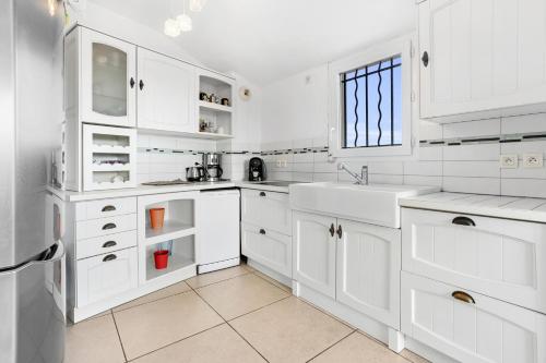 une cuisine blanche avec des armoires blanches et un évier dans l'établissement Les Terrasses de Cogolin, à Cogolin