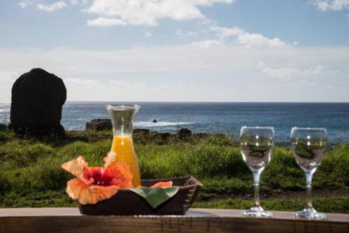 a table with two glasses and a bottle of wine at PARAÍSO Sunset Bungalows in Hanga Roa