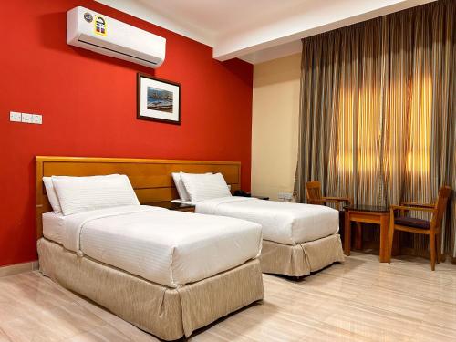 two beds in a hotel room with red walls at Remal Ibri hotel in Ibri