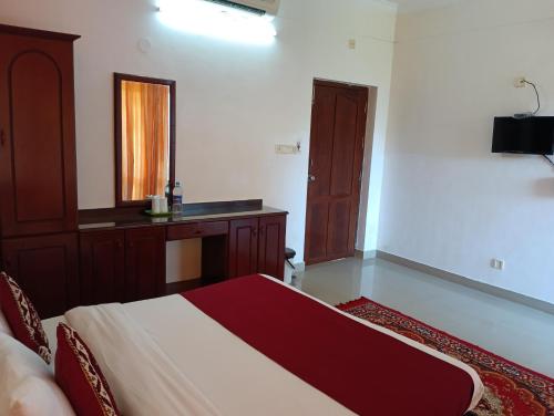 a bedroom with a bed and a desk and a mirror at Vedantha Inn in Kovalam