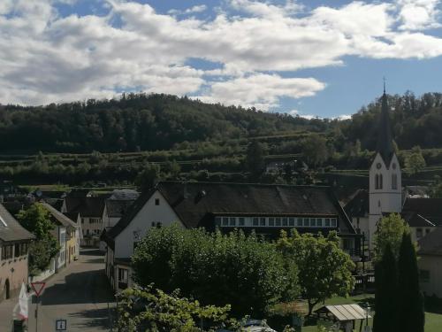 ein Dorf mit einer Kirche und einem Hügel im Hintergrund in der Unterkunft Hotel-Restaurant Rebstock in Vogtsburg