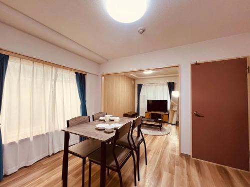 a dining room with a table and chairs and a television at HS平岸 HSHiraghishi in Minami-jūichijō