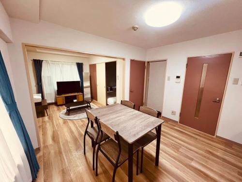 a living room with a wooden table and a television at HS平岸 HSHiraghishi in Minami-jūichijō