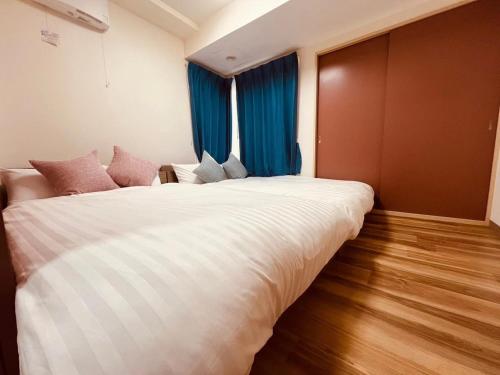 a large white bed in a room with blue curtains at HS平岸 HSHiraghishi in Minami-jūichijō