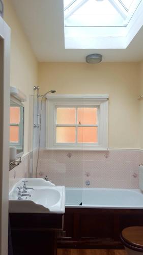 ein Bad mit einem Waschbecken, einer Badewanne und einem Fenster in der Unterkunft Rowden Mill Station in Bromyard