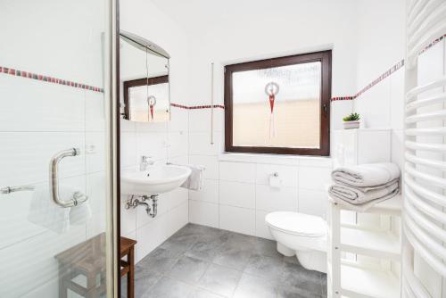 a white bathroom with a toilet and a sink at Am Pön - Ferienwohnungen in Medebach