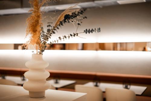 a white vase with dried flowers on a table at GINN Apartment-Hotel Stuttgart-Esslingen in Esslingen