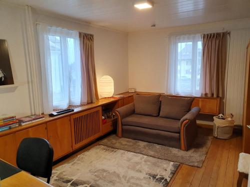 a living room with a chair and windows at Bed n Bureau Roggwil in Roggwil