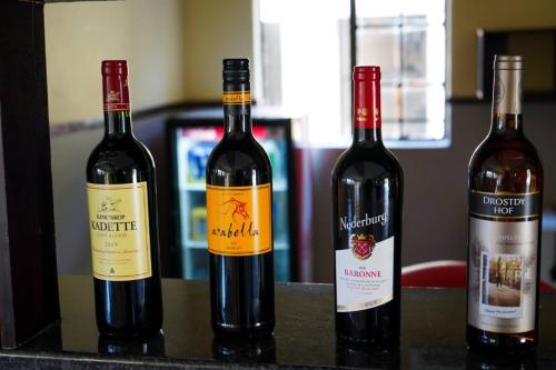 tres botellas de vino sentadas en un mostrador en River View Villa Self Catering, en Francistown