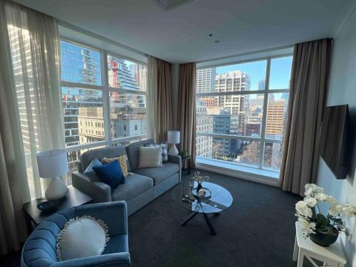 een woonkamer met een blauwe bank en een groot raam bij Exclusive Suite CBD Riverviews - ParkingOnsite in Melbourne