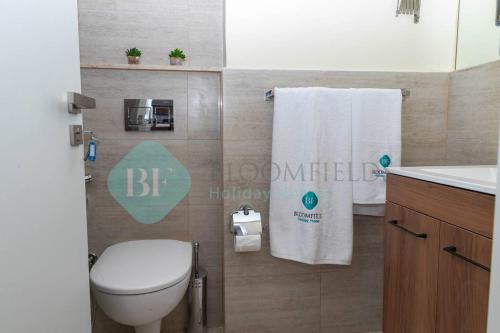 a bathroom with a toilet and a sink and towels at Grandeur Studio In Oasis in Al Qurayyah