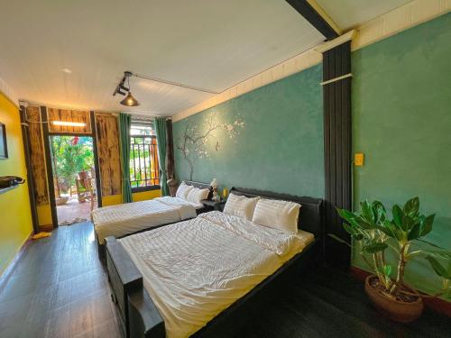 1 dormitorio con 2 camas y pared verde en Thênh Thang Home & Cafe, en Mộc Châu