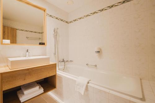 ein Badezimmer mit einem Waschbecken, einer Badewanne und einem Waschbecken in der Unterkunft Rodinný Hotel Hubert High Tatras in Vysoké Tatry
