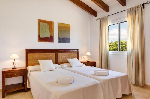 a bedroom with two beds with white sheets and a window at Villas Menorca Sur in Son Bou