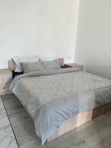 a white bedroom with a large bed with grey sheets at New Marine Apartment in Yuzhne