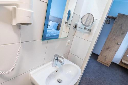 W łazience znajduje się umywalka i lustro. w obiekcie Lahn Hotel w mieście Biedenkopf