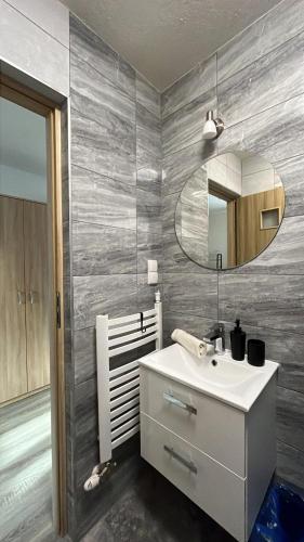 a bathroom with a white sink and a mirror at Apartamenty Cichy Kącik in Poronin