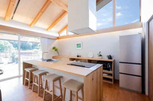 a kitchen with a large island with bar stools at 【海から近く】敷地内無料駐車場5台分完備！BBQ設備貸出あり3,500円！快適空間！【COQAEL】 in Oda