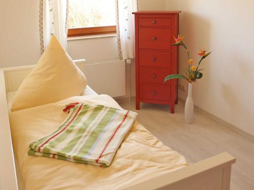 a bed with a pillow and a dresser in a room at Exkl FH Aquamarin mit Kamin 250 m zum Strand in Börgerende-Rethwisch