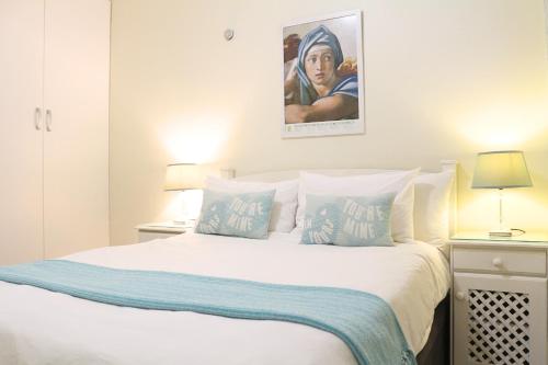 1 dormitorio con 1 cama blanca y 2 almohadas en Tyger Classique Self-Catering Cape Town, Tyger Valley, en Bellville