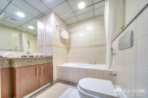 a bathroom with a toilet and a sink and a tub at Contemporary One Bedroom with Full Marina View in Dubai