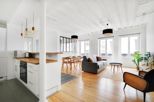 Il comprend une cuisine et un salon avec des murs blancs et du parquet. dans l'établissement Apartments in the heart of Paris in Sentier, à Paris
