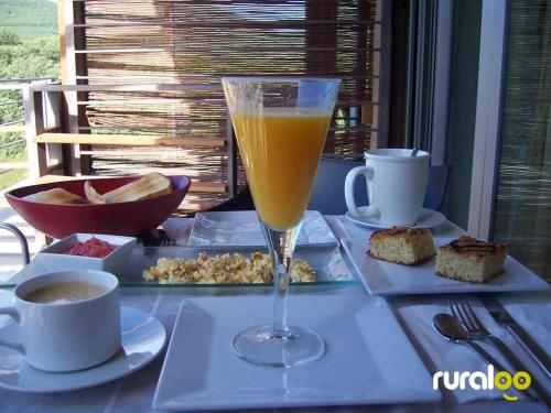 un vaso de zumo de naranja sentado en una mesa con comida en El Refugio de Cristal, en Hontanar