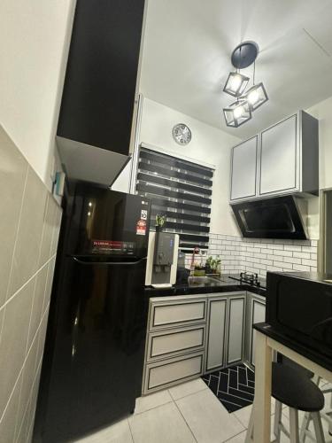 a kitchen with black and white cabinets and a black refrigerator at MK Homestay Perlis in Arau