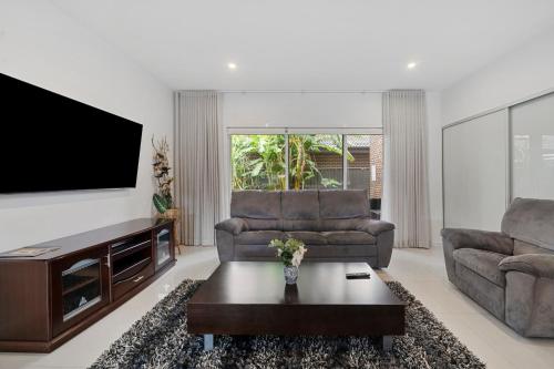 uma sala de estar com 2 sofás e uma televisão de ecrã plano em Spacious 5 Bedroom 2.5 bathroom House in Gregory Hills em Narellan