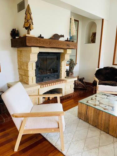 a living room with a fireplace and a chair and a table at Chalet Barcelonnette - location saisonnière in Barcelonnette