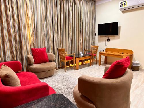 a living room with red chairs and a television at Remal Ibri hotel in ‘Ibrī