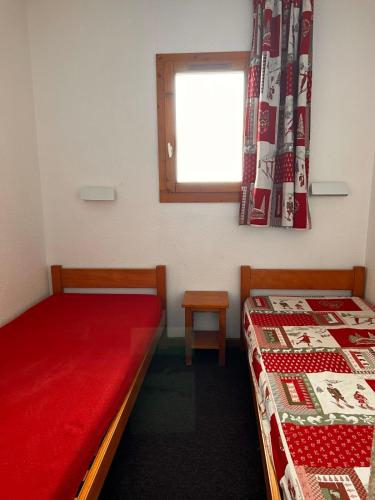 two beds in a room with a red blanket and a window at Snowflakes at La Plagne Soleil in La Plagne Tarentaise