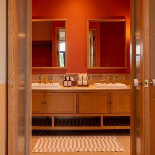 a bathroom with two sinks and two mirrors at Toscana Valley Hotel Portofino in Mu Si