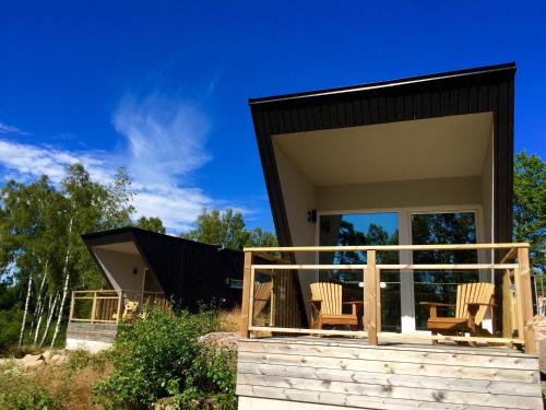 una casa con techo negro y 2 sillas en un porche en Vinbergs Stugby, en Vinberg