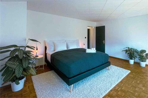 a bedroom with a bed and two potted plants at -The Urbanist- Mountainview Parking Garden 3BD in Unterseen