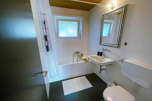 a bathroom with a toilet and a sink and a mirror at -The Urbanist- Mountainview Parking Garden 3BD in Unterseen