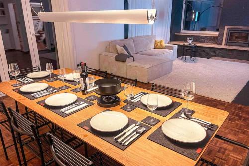 a dining room table with plates and wine glasses at -The Urbanist- Mountainview Parking Garden 3BD in Unterseen