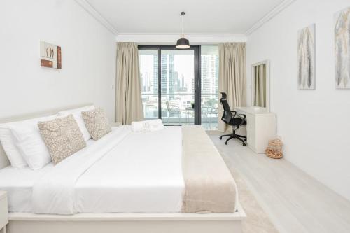 um quarto branco com uma grande cama branca e uma secretária em LUXFolio Retreats Beautiful JLT 1BR Apartment em Dubai