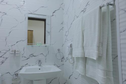 La salle de bains blanche est pourvue d'un lavabo et d'un miroir. dans l'établissement Resident Hotel, à Tachkent