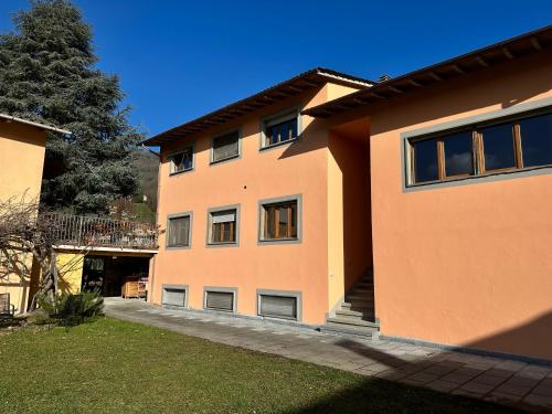 un edificio naranja con un árbol delante de él en Casa vacanza Hydrangea con piscina e giardino, en Bagni di Lucca