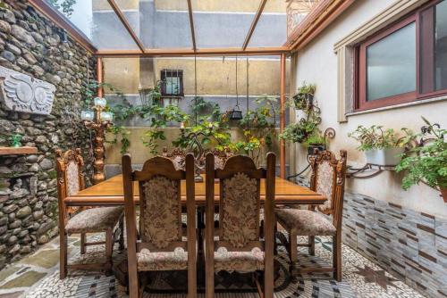a wooden table and chairs on a patio with plants at “Kanuni” - Authentic Albanian House in Shkodër