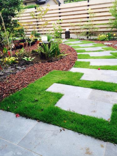 a garden with a stone pathway and grass at Den House in Oshima