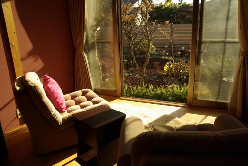 a living room with two chairs and a window at Den House in Oshima