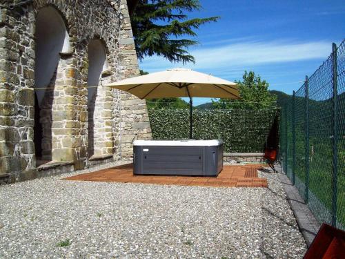 una mesa con sombrilla en el patio en Flat with heated hot tub and shared pool, en Casola in Lunigiana