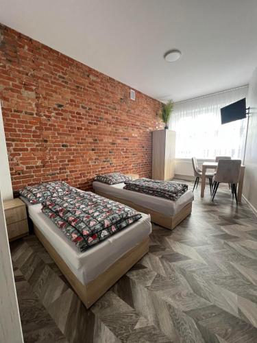 três camas num quarto com uma parede de tijolos em apartament em Skarżysko-Kamienna