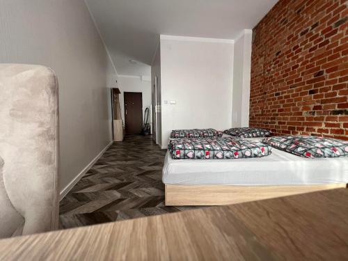 duas camas num quarto com uma parede de tijolos em apartament em Skarżysko-Kamienna